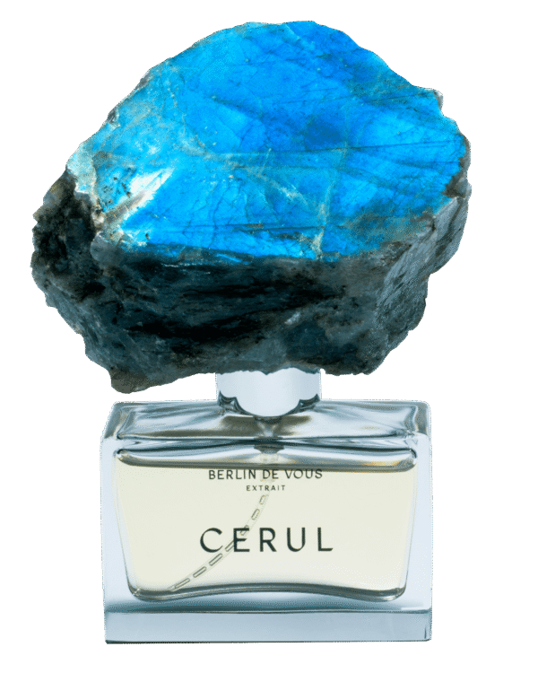Classic and elegant rectangular perfume bottle made of glass with a large labradorite lid (6 cm wide, 4 cm high and 3 cm deep - total height with lid approx. 12 cm) by BERLIN DE VOUS. Filled with 30 ml of the award-winning perfume "CERUL", a sun-yellow, slightly amber-colored and oily liquid. The brand name and the name of the fragrance are prominently centered on the glass bottle in a classically modern black font. The clasp is a large, hand-carved labradorite. The surface alternates between untreated and smooth, highly iridescent surfaces that reflect all the colors of the rainbow. The stone weighs around 300 to 350 grams, making each bottle a unique collector's item.     